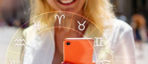 Donna con cellulare e ruota dei segni zodiacali - Foto da © Pixabay.