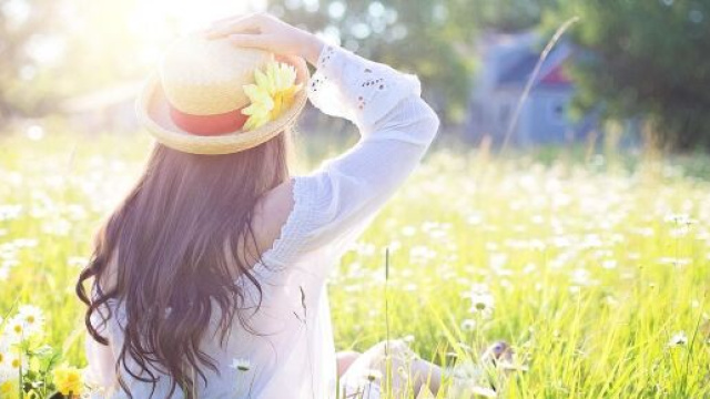 Figura di spalle in un prato fiorito con cappello di paglia – © Pixabay.