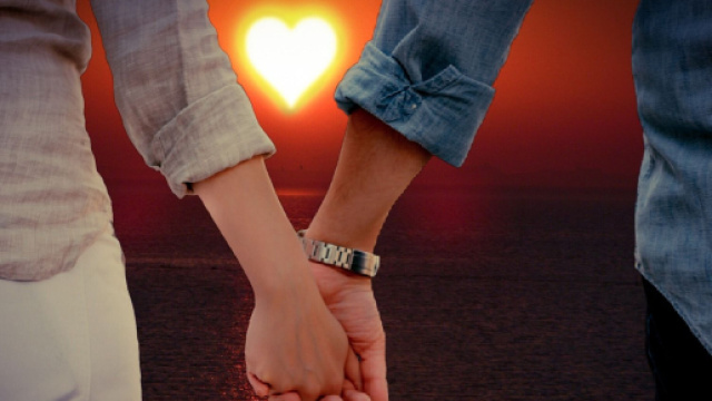 Mano nella mano di una coppia con cuore sullo sfondo - © Pixabay.