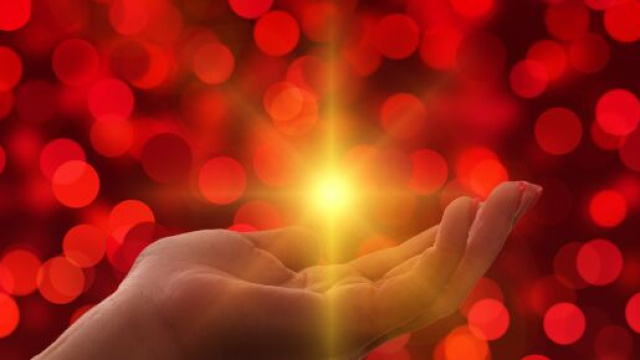 Mano aperta con luce brillante su sfondo bokeh – © Pixabay IA.