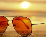 Occhiali da sole su una spiaggia al tramonto (©pixabay.com).