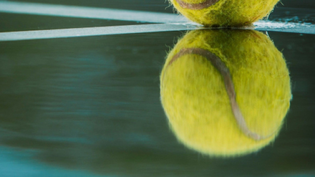 Pallina da tennis su superficie riflettente © Unsplash.