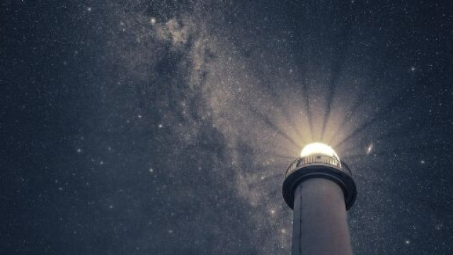 La luce di un faro illuminato mostra una galassia &copy; Pixabay.