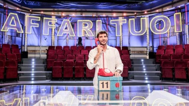 Affari tuoi, il look minimal di De Martino: camicia bianca, pantaloni neri e cravatta